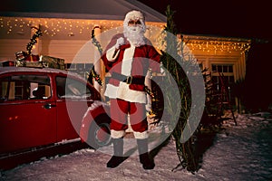 Santa Claus carrying a big sack of gifts outdoors, near house.