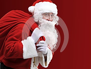 Santa Claus carrying huge red sack with presents