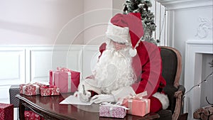 Santa Claus checking presents and making notes in the list of children`s wishes
