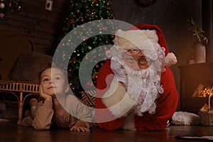 Santa Claus and child laying on floor at home. Christmas gift. Family holiday concept