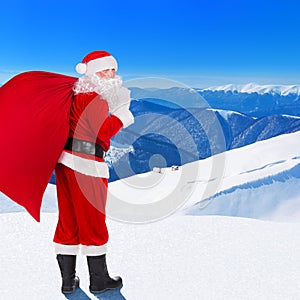 Santa Claus with Christmas bag against snow winter mountain land