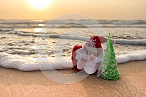 Santa Claus and Christmas tree on the beach or sandy sea shore. Christmas and New Year celebration travel concept