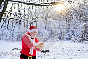 Santa Claus with Christmas wish list comes in the snow forest.