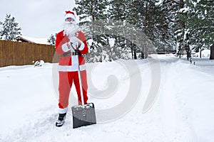 Santa Claus cleans snow with shovel in winter outdoors after a snowfall. Cleaning the streets in the village, clearing the passage