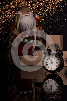 Santa Claus, clock and christmas gift on a black background