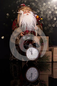 Santa Claus, clock and christmas gifts on a black background