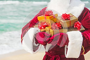 Santa Claus close up with many golden gifts on sea beach