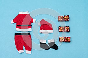 Santa Claus clothes and little red presents on blue background