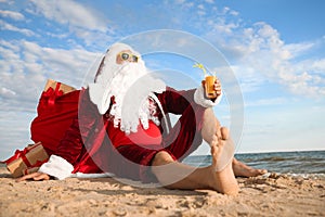 Santa Claus with cocktail relaxing on beach. Christmas vacation