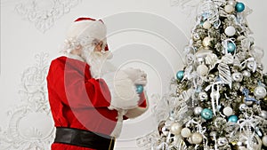 Santa Claus decorating Christmas tree with baubles