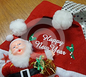 Santa Claus doll and white Happy New Year message on red Santa hat