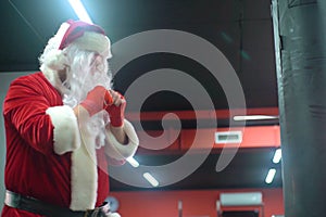 Santa Claus Fighter kickbox With Red Bandages boxer hitting a huge punching bag at a boxing studio. Santa Claus boxer