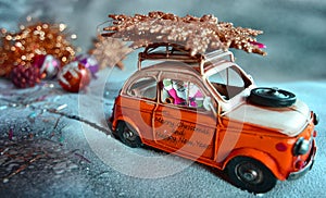 Santa Claus flees with an orange car, on the snow, with Christmas decorations