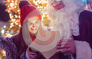 Santa Claus giving presents in front of Christmas Tree