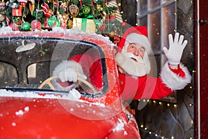 Santa claus greeting while driving a red retro car. Merry Christmas