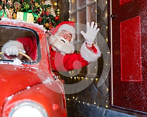 Santa claus greeting while driving a red retro car. Merry Christmas