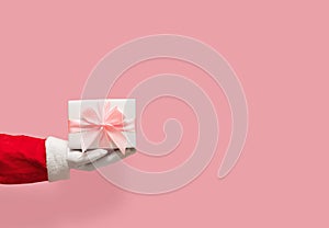 Santa Claus hand holding gift box on pink isolated background