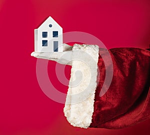 Santa Claus hand holding model house. New House in new year, concept