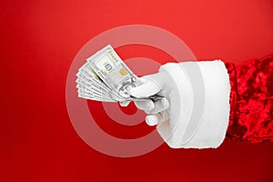 Santa Claus hand holding money on red background. Hand with cash