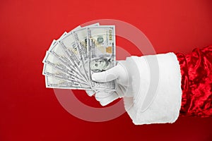 Santa Claus hand holding money on red background. Hand with cash