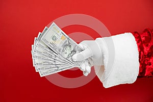 Santa Claus hand holding money on red background. Hand with cash