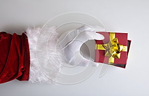 Santa Claus hands uncovering gift on white table