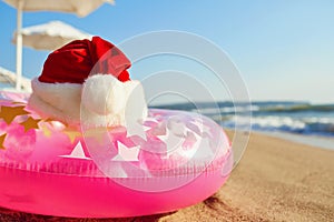 Santa Claus hat on the beach by the sea. Christmas on vacation b