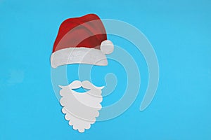 Santa Claus hat and beard on light blue background. Christmas and New Year concept