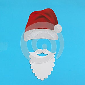 Santa Claus hat and beard on light blue background. Christmas and New Year concept