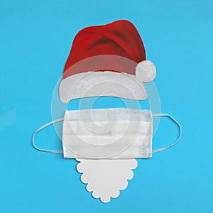 Santa Claus hat and beard with medical mask on light blue background. Christmas and New Year concept