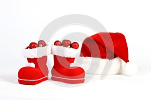 Santa Claus hat and boots with red and matt christmas balls on snow in front of white background photo