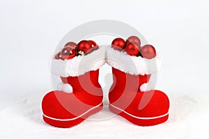 Santa Claus hat and boots with red and matt christmas balls on snow in front of white background photo