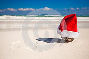 Santa Claus hat at coconut on a white sandy beach