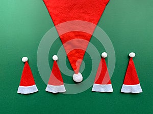 Santa Claus hat with few small Christmas hats. Abstract design on green background.