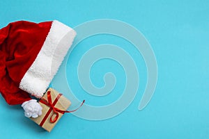 Santa Claus hat and gift box on light blue background. Christmas and New Year concept