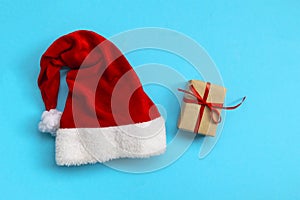 Santa Claus hat and gift box on light blue background. Christmas and New Year concept