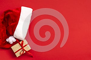 Santa Claus hat and gift box on light red background. Christmas and New Year concept