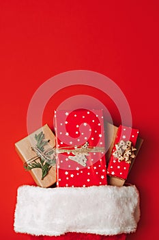 Santa Claus hat with gift boxes on red background. Christmas presents and santa hat on red background. Xmas gift ideas