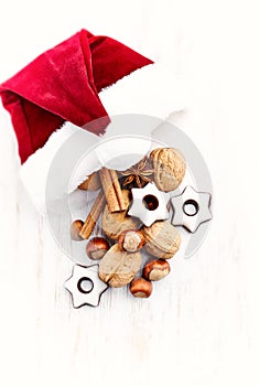 Santa Claus hat with nuts, spices and chocolates. Christmas background