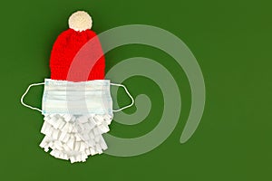 Santa Claus hat and paper beard with medical  face mask on classic green background, creative minimal concept of Christmas and New