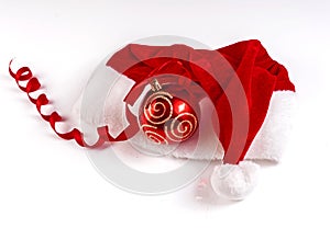 Santa Claus hat and red balloons on a white background.Santa Claus hat and red ball with gold ornaments on a white background.
