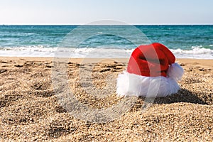 Santa Claus hat on sandy beach. Creative Christmas or New Year concept