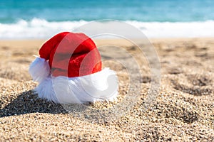 Santa Claus hat on sandy beach. Creative Christmas or New Year concept