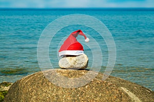 Santa Claus hat on stones near sea