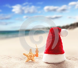 Santa Claus hat on white sand of tropical beach. Christmas or New Year`s concept