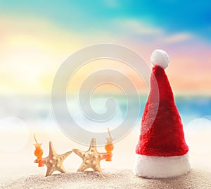 Santa Claus hat on white sand of tropical beach. Christmas or New Year`s vacation concept.