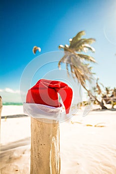 Santa Claus hat on white sandy beach in sunny day