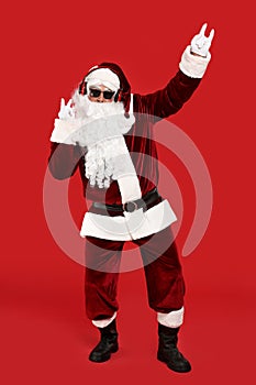 Santa Claus with headphones listening to Christmas music on red background