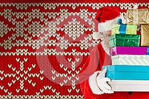 Composite image of santa claus hiding behind stack christmas gifts