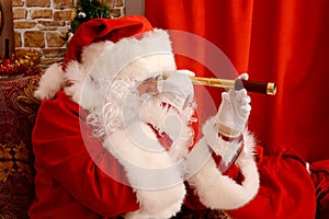 Santa Claus at his home, holding spyglass, preparing for travel